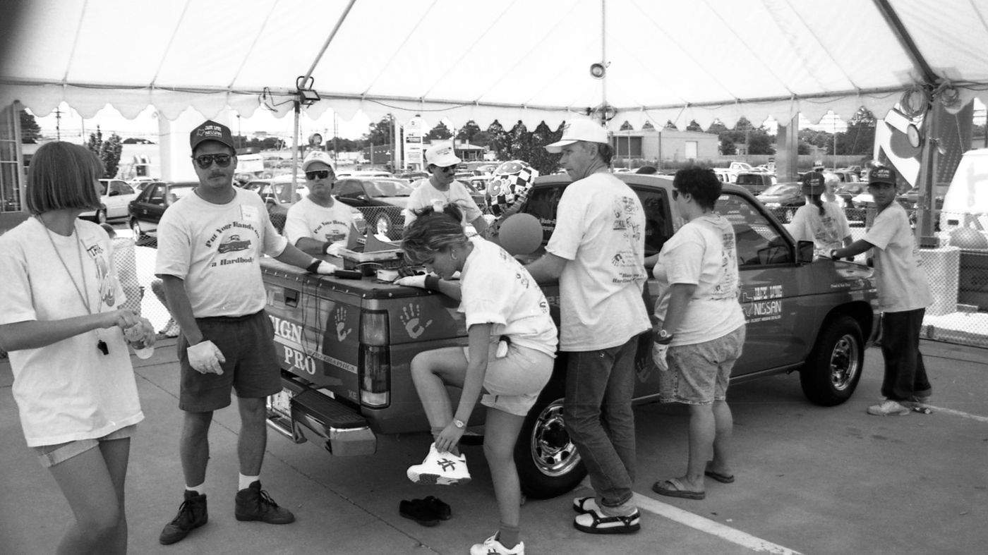 A contestant changes her shoe with one hand still on the truck's tailgate